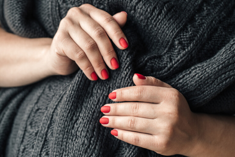 63.0 a woman in a dark knitted sweater shows a red PNGCQ3X scaled