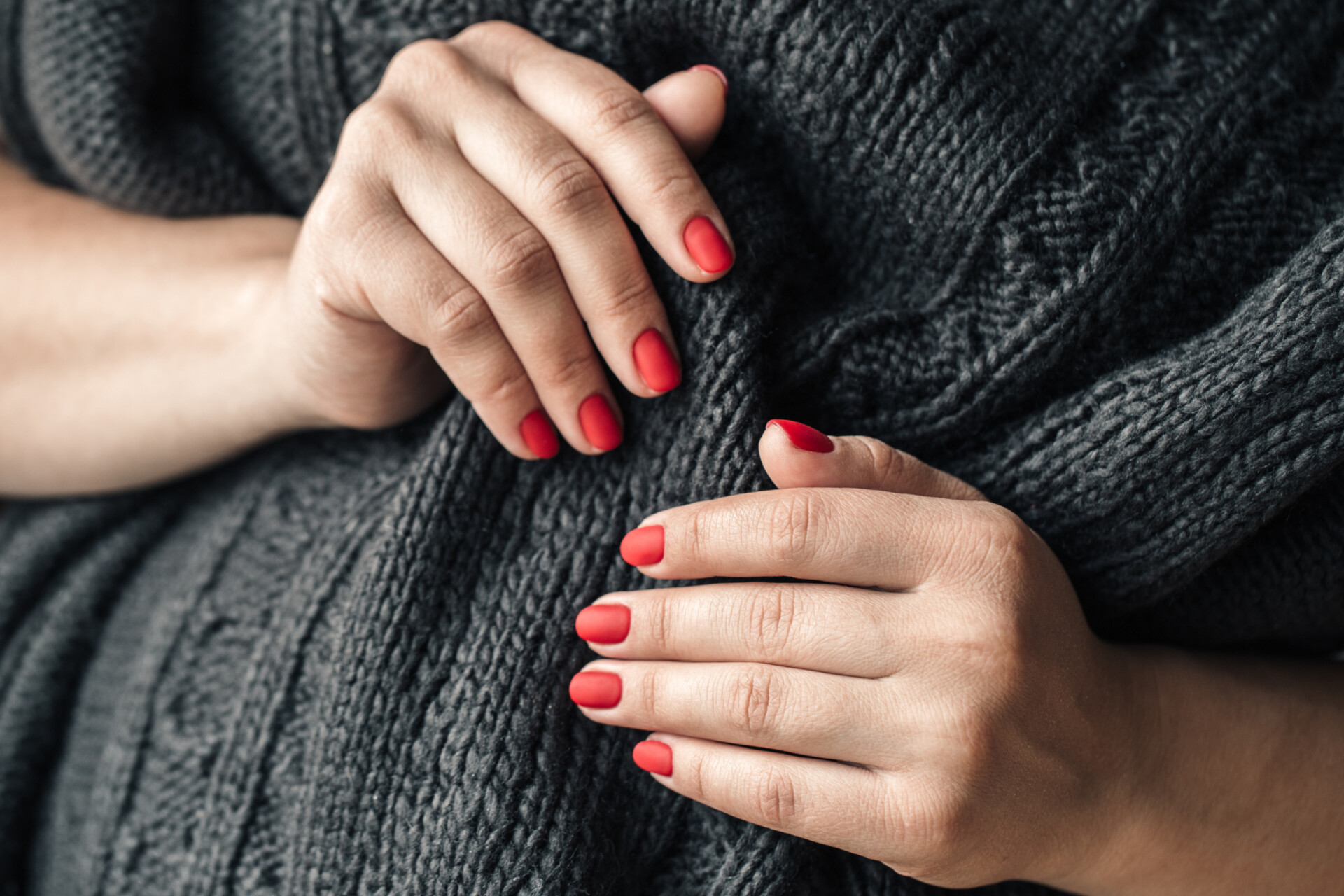 63.0 a woman in a dark knitted sweater shows a red PNGCQ3X scaled